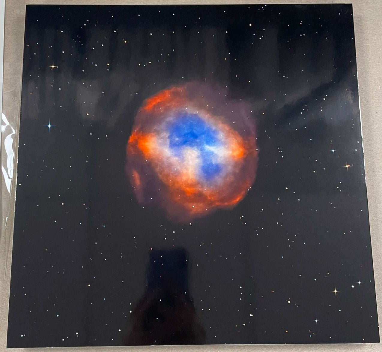 Starry night sky print with a colorful nebula on a black background, held by a person.