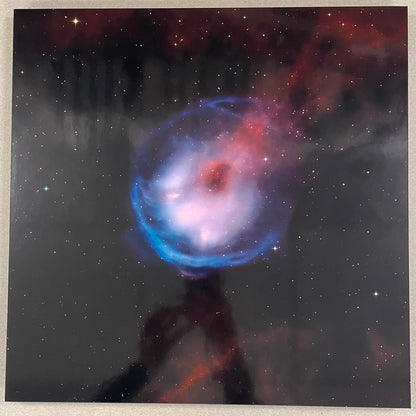 Framed photograph of a colorful nebula on a beige wall.
