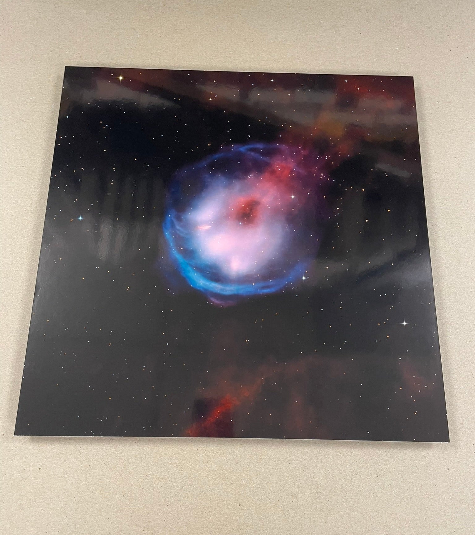 Framed photograph of a colorful nebula on a beige wall.