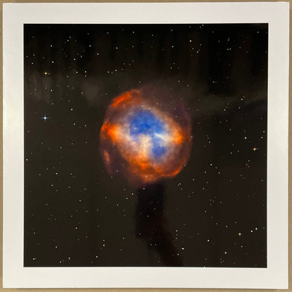 Framed photograph of a colorful nebula on a brown background