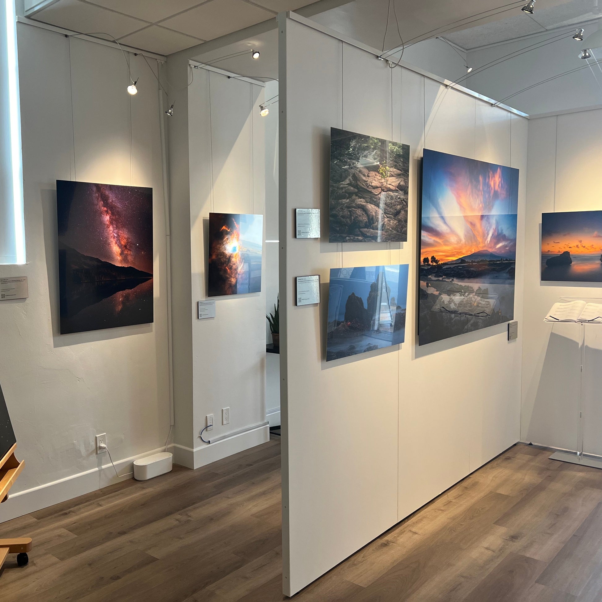 A photograph of the interior of Slice of Light Gallery taken from the vantage point of the manager's office, showing multiple metal prints on display on the walls and partitions.