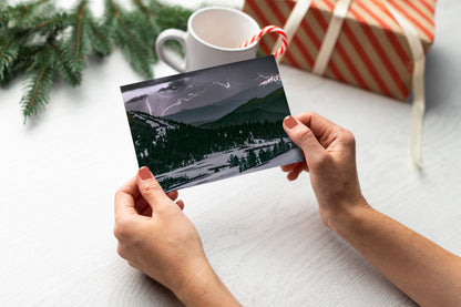 A digital mockup of a greeting card featuring the photograph titled "Lightning and Ice" being held in someone's hands with christmas tree detail out of focus in the background.