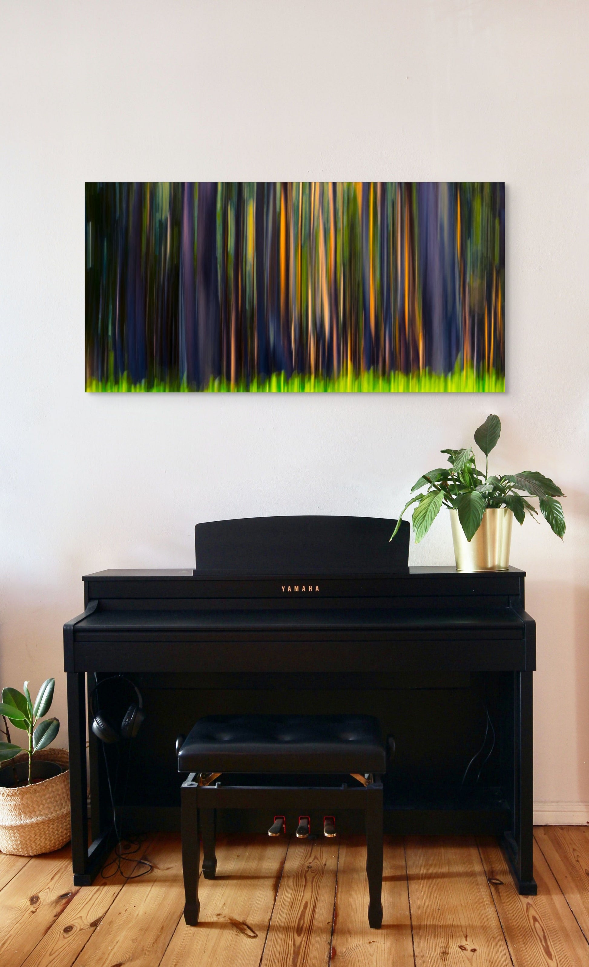 A wall art mockup featuring the photograph titled "Rainbow Eucalyptus, Big Island" by landscape photographer Ben Coffman as a 48 inch wide metal print with inset frame on display above piano in a modern apartment.