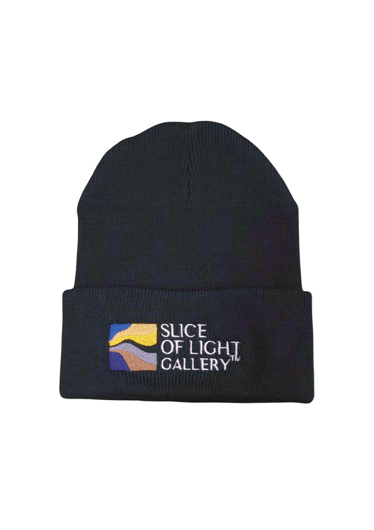 A photograph of a black beanie with colorized Slice of Light logo embroidery with background removed.