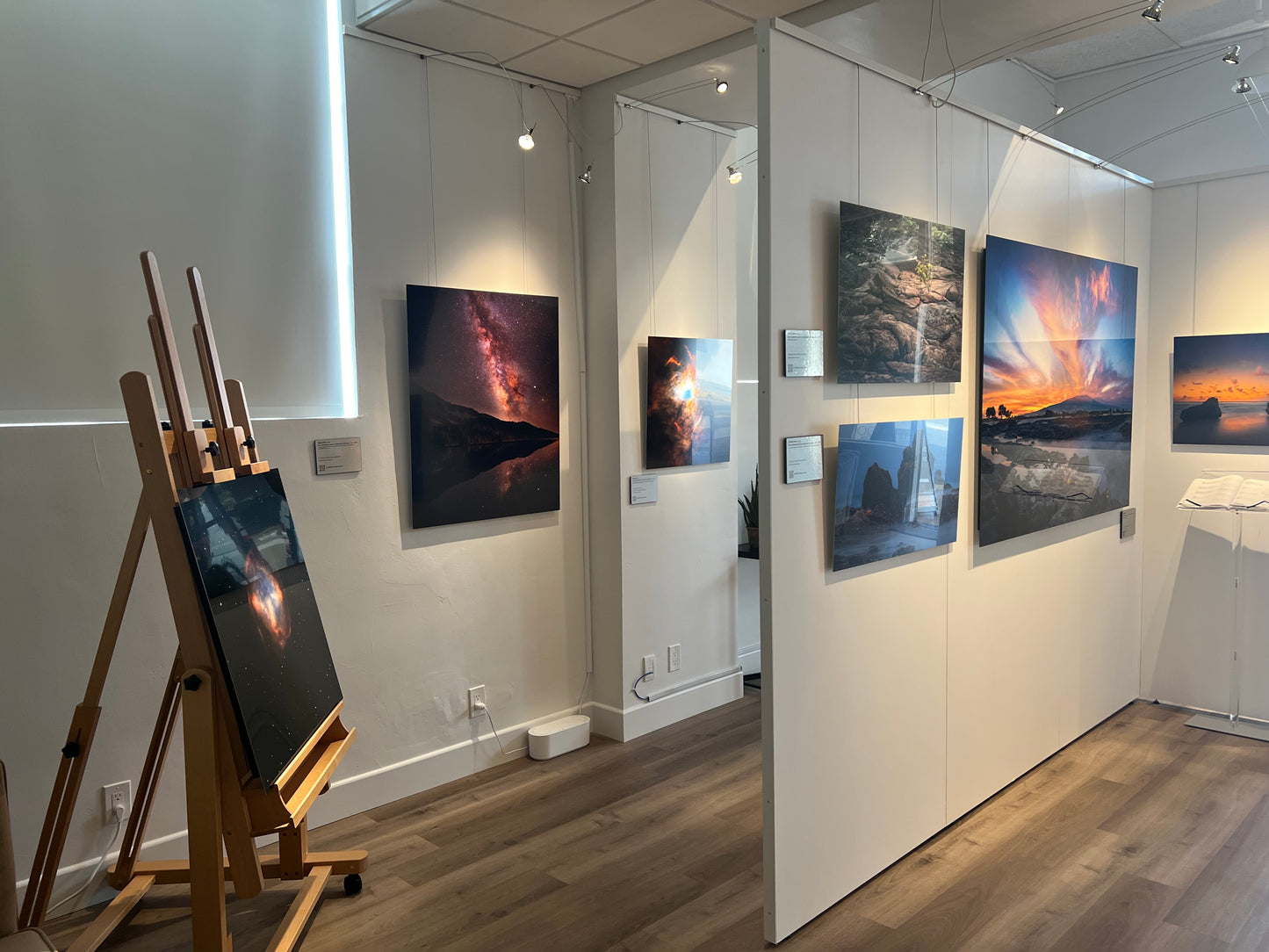 A photograph of the interior of Slice of Light Gallery showing multiple metal prints displayed on the walls and partitions.