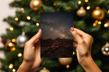 A digital mockup of a greeting card featuring the photograph titled "The High Road" being held in someone's hands with christmas tree detail out of focus in the background.