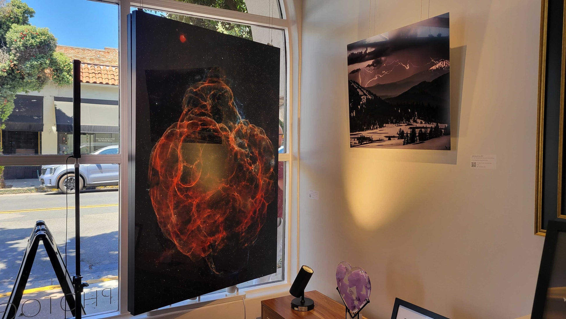 A photograph of the interior of Slice of Light Gallery facing the window showing the two metal prints titled "Web of Wisps" and "Lightning and Ice".