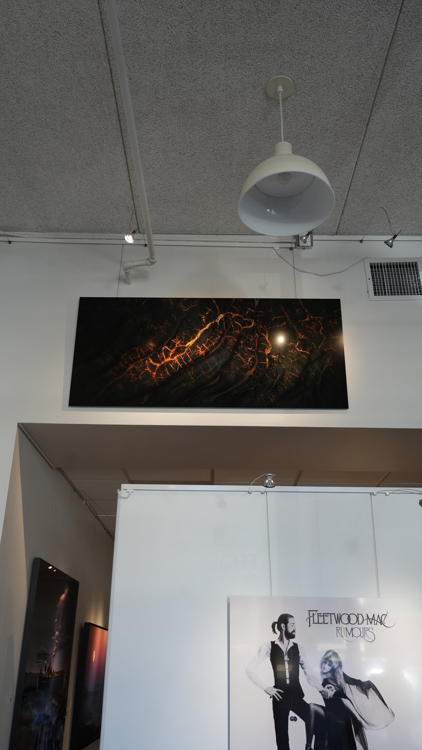 Artistic abstract painting on a wall with a white ceiling light fixture above.