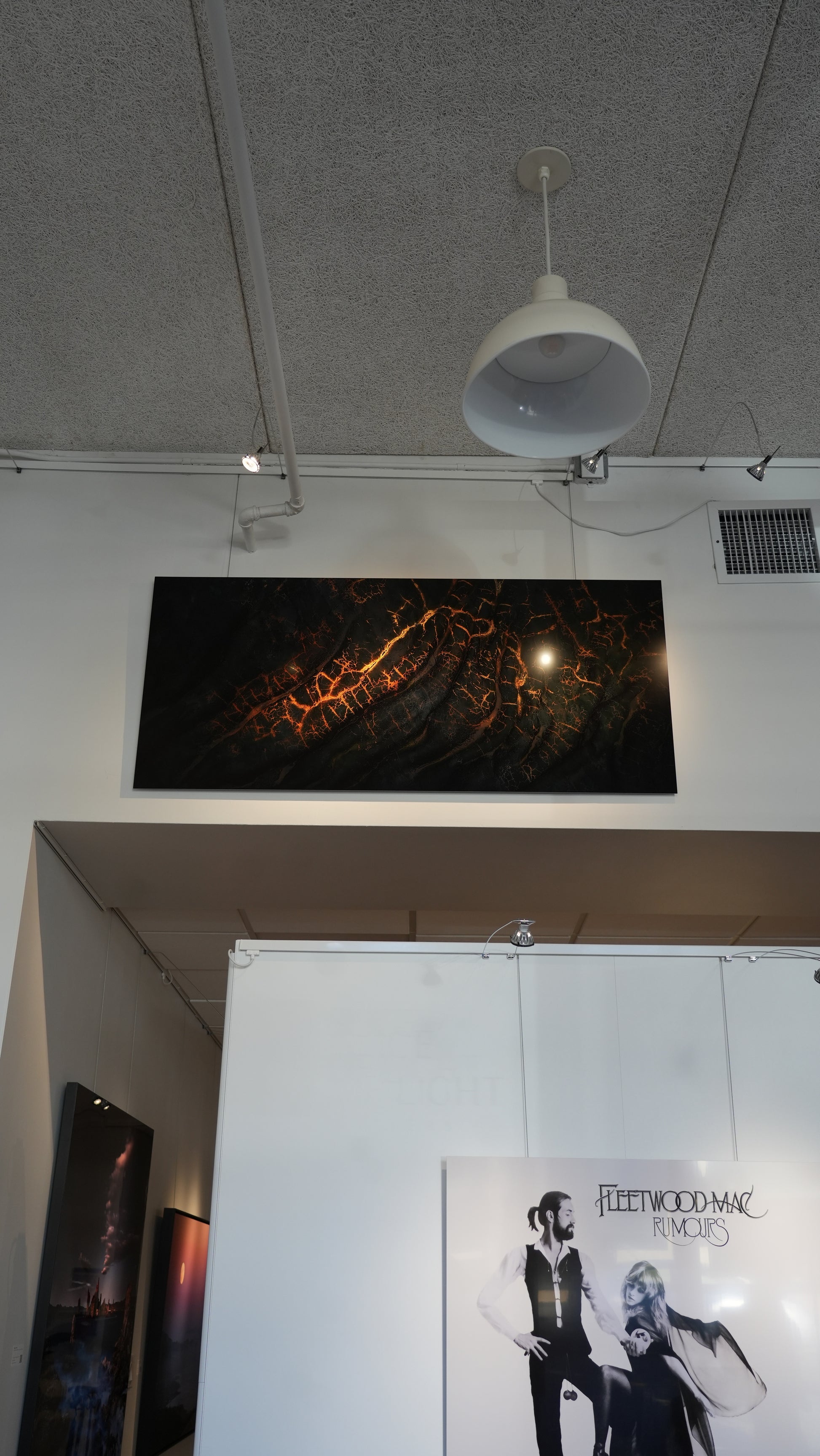 Artistic abstract painting on a wall with a white ceiling light fixture above.