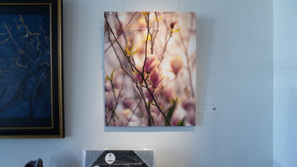 Framed artwork of a floral branch on a wall with another piece of art and a box below.