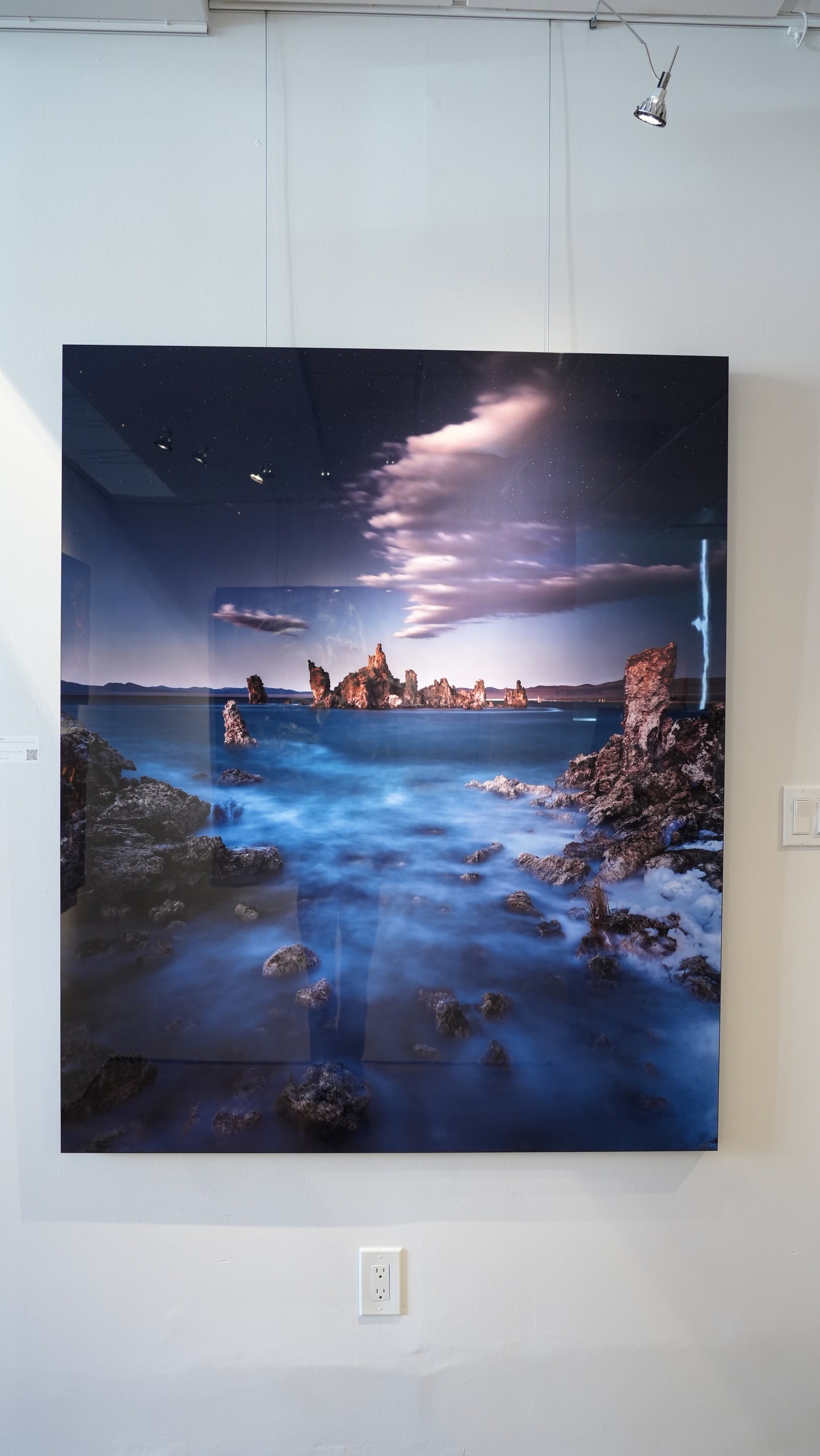 Large photograph of a coastal scene with rocks and water on a white wall.