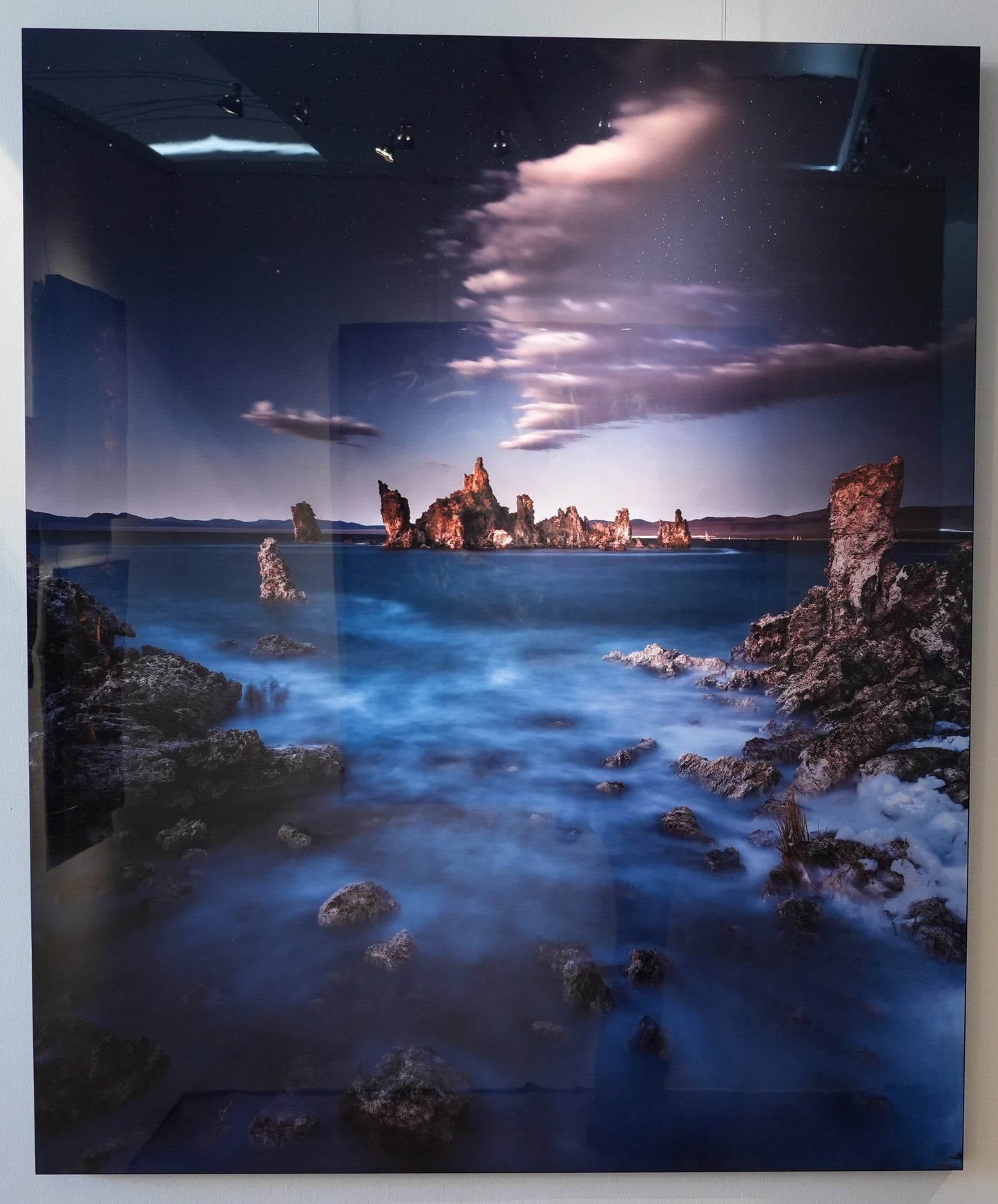 Two wall-mounted artworks depicting coastal scenes with sunset and cityscape.