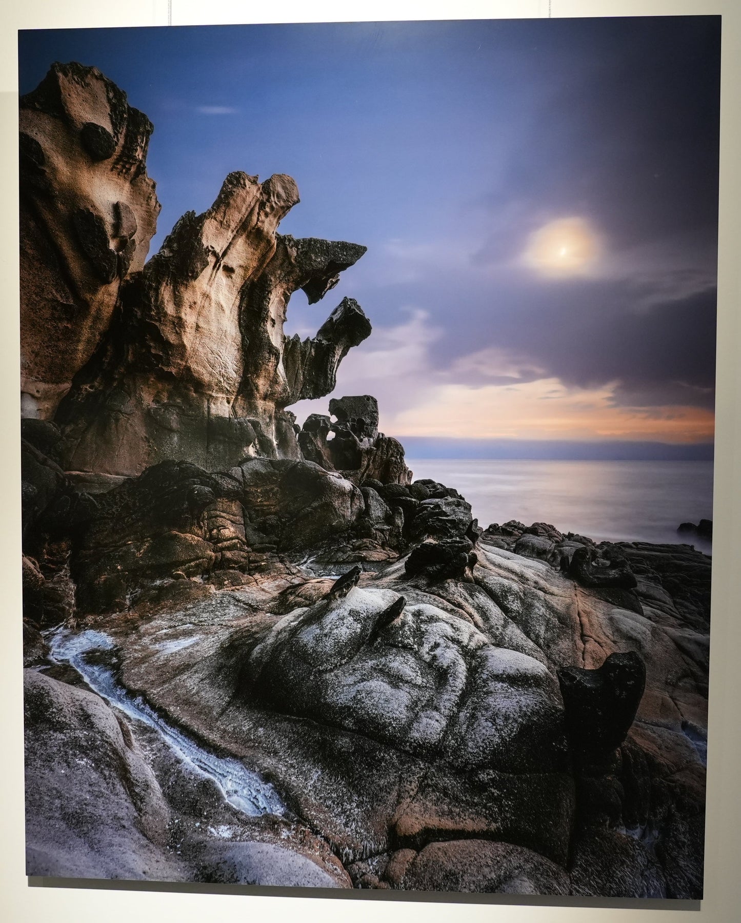 Large photograph of a rocky landscape with a sunset or sunrise displayed on a wall.