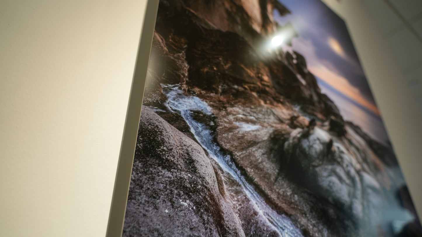 Close-up of a large wall art print depicting a natural landscape with rocks and water.