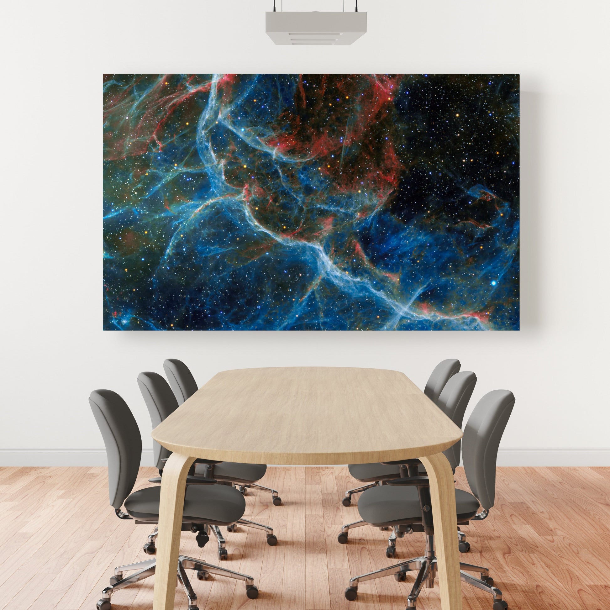 A wall art mockup featuring the metal print titled "Blue Vela" displayed prominently in a large conference room with elliptical wood table gray upholstered rolling armless chairs and slat mahogany wood flooring