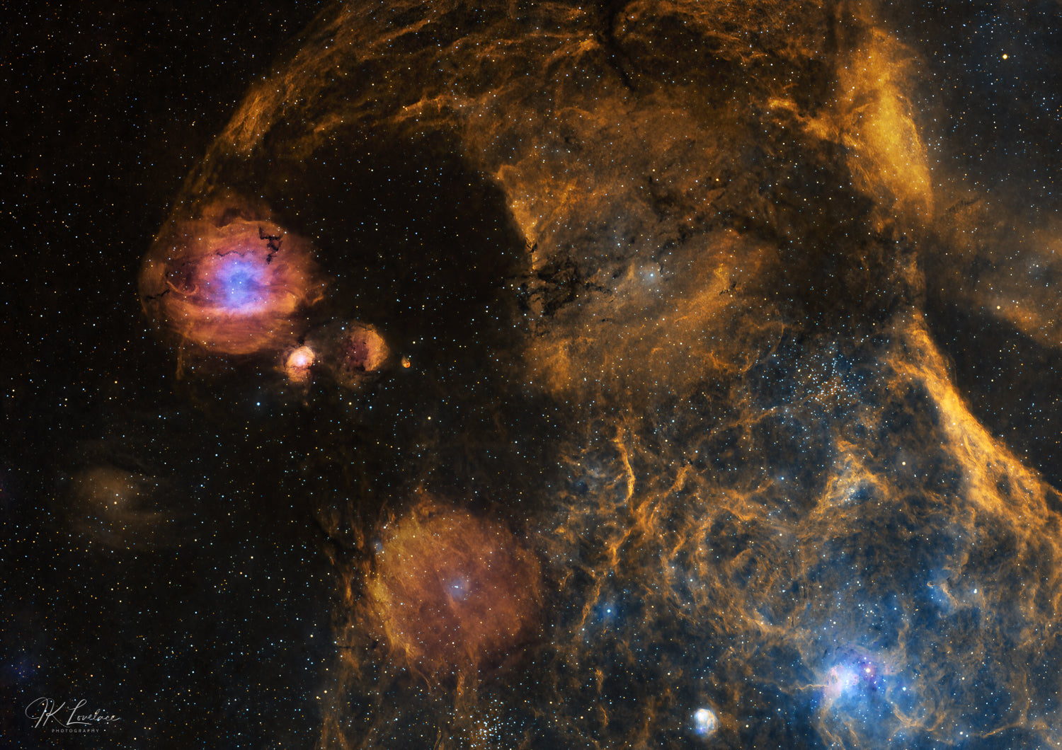 A jpg of the astrophotograph titled "Cosmic Marbles" shot by astrophotographer J K Lovelace featuring dynamic looking region of the constellation Auriga where spherical nebulas appear hurled to crash into each other. This image features the nebulas Sh2-232, Sh2-235, Sh2-231, Sh2-234, and LBN 796, along with the open star clusters M38 and M36.